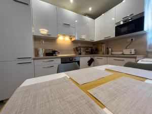 a kitchen with white cabinets and a table with chairs at COZY apartment in GREAT location in Košice