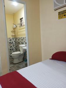 a bedroom with a bed and a bathroom with a toilet at Moalboal Indino's Guesthouse sardines run and sea turtle 1 minute walking distance in Moalboal +41 photos