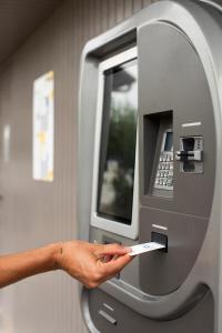 a person is putting a ticket into an atm machine at The Originals Access H&ocirc;tel Bordeaux A&eacute;roport in M&eacute;rignac