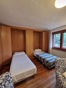 a room with two beds and two chairs in it at L'Atelier du Temps - Sole e Luna in Cogne