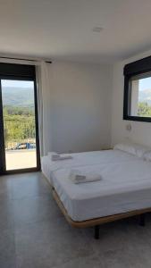 Habitación blanca con cama y ventana en Casa rural Atalanta de la Vera, en Jaraíz de la Vera