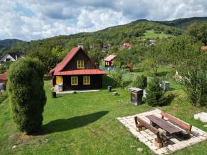 Chalupa U Měšťanů في Lužná: منزل صغير في حقل مع مقعد