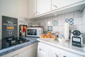 una cocina con estufa horno superior junto a un microondas en L'Évasion Aulnaysienne - Appt pour 4, en Aulnay-sous-Bois 6 fotos más
