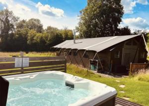 a hot tub in a field next to a tent at Seven Hills Hideaway - Blorenge in Llanvetherine