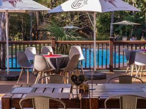 um grupo de mesas e cadeiras com guarda-sóis ao lado de uma piscina em Kruger Park Lodge Unit 538 - PmP em Hazyview
