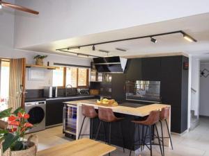 uma cozinha com armários pretos e uma ilha com bancos de bar em Kruger Park Lodge Unit 538 - PmP em Hazyview