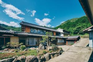 a house with mountains in the background at 和紙にまみれるワラビーランド in Mino