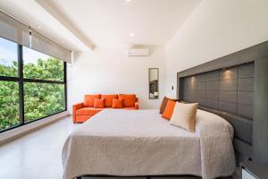 1 dormitorio con 1 cama grande y 1 sofá naranja en 2099 - Casa Hera, en Santa Cruz Huatulco