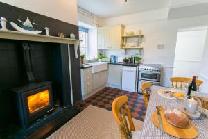 a kitchen with a fireplace and a table with food on it at Bears Cottage in Moelfre