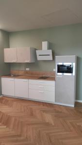 a kitchen with white cabinets and a wooden floor at La Morra 66 in La Morra