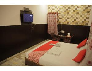 HOTEL SANDS INN, Jodhpur في جودبور: غرفة نوم بسرير وتلفزيون وطاولة