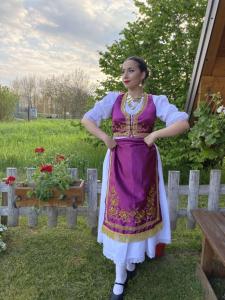 a woman in a purple and white dress standing next to a fence at Lolini bungalov in Novi Sad