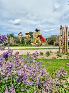 un jardín con flores púrpuras y un parque infantil en TopParken – Parc IJsselhoeve, en IJssellaan