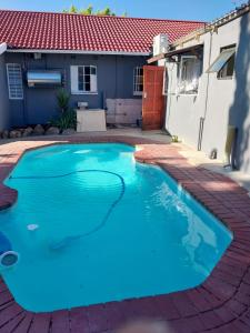 a blue swimming pool in front of a house at Home Life Guesthouse in Midrand