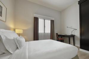 AC Hotel by Marriott Penang في بايان ليباس: غرفة نوم مع سرير أبيض كبير ومكتب