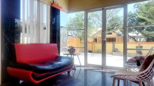 ein Wohnzimmer mit einem roten Stuhl und einem Fenster in der Unterkunft SASANDO RESIDENCE KUPANG in Maulafa