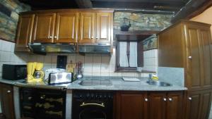 a kitchen with wooden cabinets and a black dishwasher at Casa Rosario in Cortina
