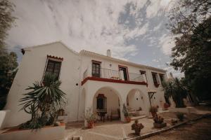 une maison blanche avec un balcon et des plantes devant elle dans l'établissement Finca Santa Margarita, à Santaella
