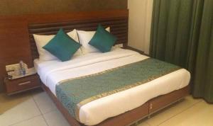 Una cama con almohadas verdes en una habitación de hotel en HOTEL 24x7 INN en Jalandhar
