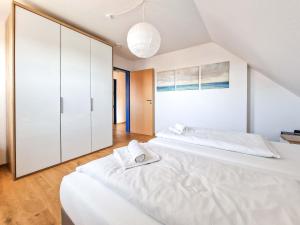 two beds in a bedroom with white cabinets at Steuerbord in Greetsiel