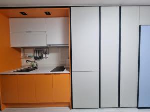 a kitchen with orange and white cabinets and a sink at Yolo House in Daegu