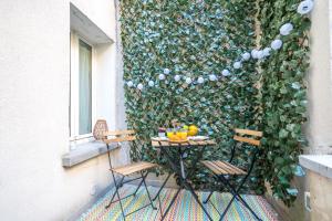a table and chairs on a balcony with a green wall at Happy Stay Paris - Cosy Studios - 5 min to Eiffel Tower in Paris