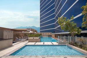 Doubletree By Hilton Fujairah City في الفجيرة: مسبح امام مبنى طويل