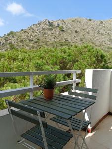 une table de pique-nique verte avec une plante en pot sur un balcon dans l'établissement Piso moderno con piscina Siesta 2, à Port d'Alcúdia