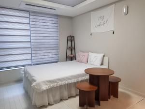 a bedroom with a bed and a table and a window at Yolo House in Daegu