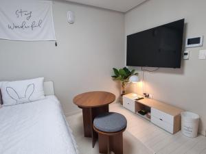 a bedroom with a bed and a table and a tv at Yolo House in Daegu