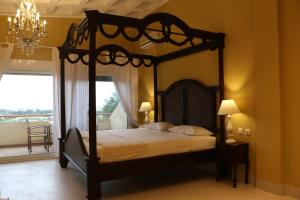 a bedroom with a canopy bed and a balcony at Kelyfos Hotel in Neos Marmaras