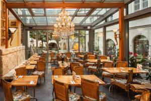 a restaurant with wooden tables and chairs and a chandelier at Iron Gate Hotel & Suites Prague by BHG in Prague