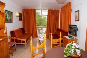 a living room with orange curtains and a table and chairs at Bon Aire Apartamentos in Paguera