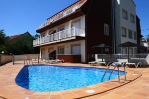 a swimming pool in front of a house at Apartamentos Coral Do Mar I in Portonovo