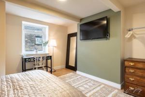 a bedroom with a bed and a desk and a tv on the wall at Cosy Cottage in Heart of Glossop in Glossop +2 photos