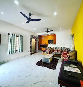 a living room with a couch and a ceiling fan at Tranquil Haven Villa Homestay in Mysore