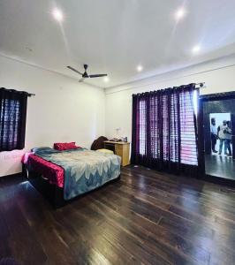 a bedroom with a bed and a wooden floor at Tranquil Haven Villa Homestay in Mysore