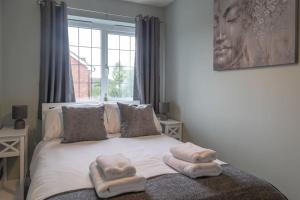 a bedroom with a bed with towels on it at Woodpecker House By RentMyHouse in Hereford