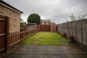 a backyard with a fence and a grass yard at Woodpecker House By RentMyHouse in Hereford