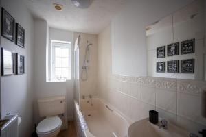 a bathroom with a tub and a toilet and a sink at Woodpecker House By RentMyHouse in Hereford