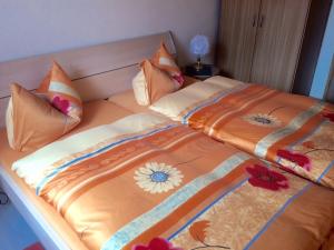 ein Bett mit einer orangefarbenen Bettdecke mit Blumen darauf in der Unterkunft Ferienwohnung Thale in Thale