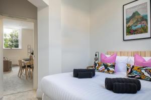 - une chambre avec un grand lit blanc et des oreillers roses dans l'établissement Apartment 1 Y Capel, Free on site parking, Central to town and a55 expressway, à St Asaph