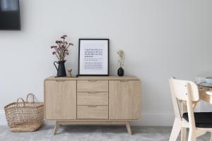 a wooden dresser in a living room with a table at Apartment 1 Y Capel, Free on site parking, Central to town and a55 expressway in St Asaph
