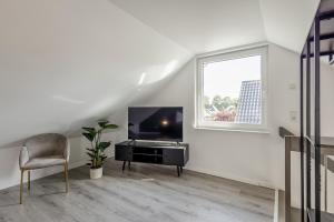 a white living room with a television and a chair at Luxus Wohnung I Gasgrill I Smart-TV I Balkon in Gütersloh