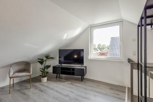 a white living room with a television and a chair at GT-City Suite 01 I Gasgrill I Smart-TV I Balkon in Gütersloh