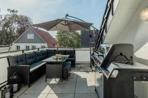a patio with a couch and a table and an umbrella at Luxus Wohnung I Gasgrill I Smart-TV I Balkon in Gütersloh