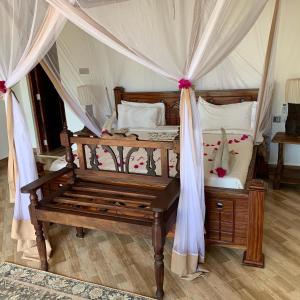 a bedroom with a canopy bed with a bench at Zi Villa Garden Room 1 in Matemwe
