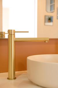 a bathroom with a white sink and a gold faucet at Appartement en front de mer avec vue imprenable sur la grande plage des Sables d'Olonne in Les Sables-dʼOlonne +14 photos