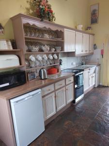 a kitchen with white cabinets and a white refrigerator at Drumaneir Cottage in Carrickmore