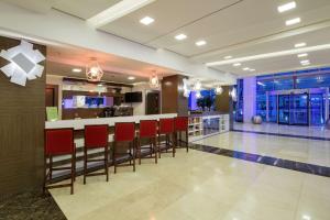 a hotel lobby with a bar with red chairs at Hampton By Hilton Gaziantep in Gaziantep